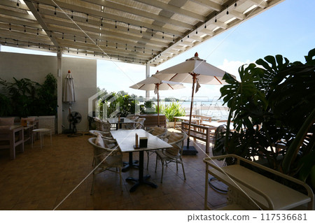 A table for eating in a dry coastal restaurant overlooking the sand, rocks and sky on a clear day. A table for eating in a dry coastal restaurant overlooking the sand, rocks and sky on a clear day. 117536681