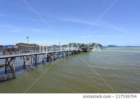 A wooden bridge leads into the sea at a resort on a clear day at Samae San Bay in Chonburi Province in Thailand. A wooden bridge leads into the sea at a resort on a clear day at Samae San Bay in Chonburi Province in Thailand. 117536704