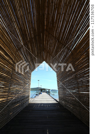 A tunnel made of bamboo sits on a bridge that stretches into the sea. A tunnel made of bamboo sits on a bridge that stretches into the sea. 117536708