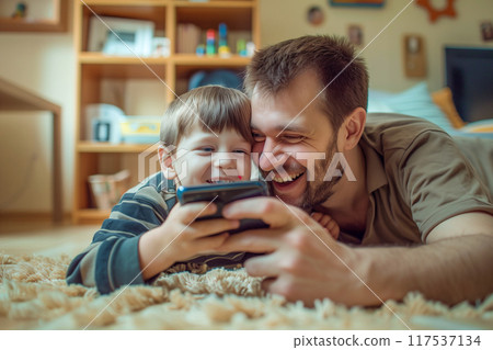 A man and a boy are laying on the floor playing a video game 117537134