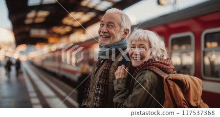 Portrait of happy pensioners on the station platform, next to the train. An elderly couple travels by train by rail 117537368