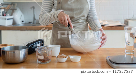 Woman Whisking Ingredients in Glass Bowl for Home Baking Project 117537587