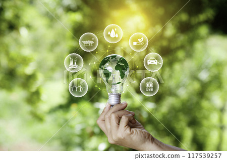green energy concept. world icon in light bulb on hands with green nature background. green energy icon around. energy reusing for maximum benefit. ESG concept for environmental, social, ethical. 117539257