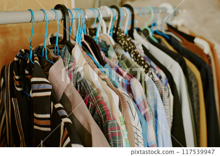 Different types of shirts hanging on a clothes rack in a cozy room Creating an organized and visually appealing clothing arrangement in soft ambient light 117539947