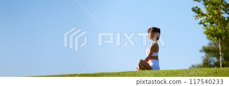 Banner. Young woman sitting peacefully outdoor in meditative posture, embracing mindfulness and mental clarity 117540233