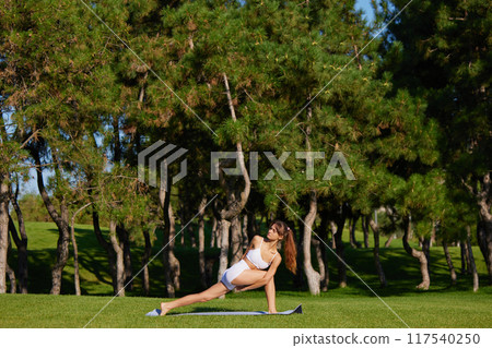 Young woman combines stretching with meditation, fostering her flexibility, core stability, and mental well-being 117540250