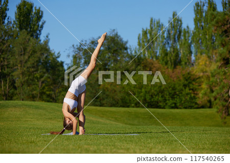 In peaceful outdoors, woman during yoga session that targets core strength and flexibility, key for enhancing overall body stability and control. In peaceful outdoors, woman during yoga session that targets core strength and flexibility, key for enhancing overall body stability and control. 117540265