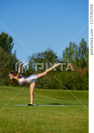 Focused on yoga practice, woman strengthens core and improves flexibility, essential for better posture and strong, stable body. 117540268