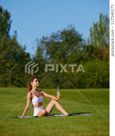 Young woman dressed activewear rest during yoga session, drinks adds nutrition and refreshes during breaks between approaches. 117540273