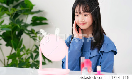 Girl applying makeup while looking in the mirror Kids cosmetics Girl applying makeup while looking in the mirror Kids cosmetics 117541166
