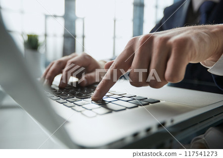 Young man presses his finger on the computer at the table in the office, close-up. 117541273