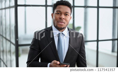 Young african american businessman held smartphone in his hands, typing message, chatting with friends in social networks 117541357