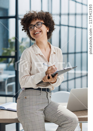 girl in the office smiles writing notes girl in the office smiles writing notes 117541393