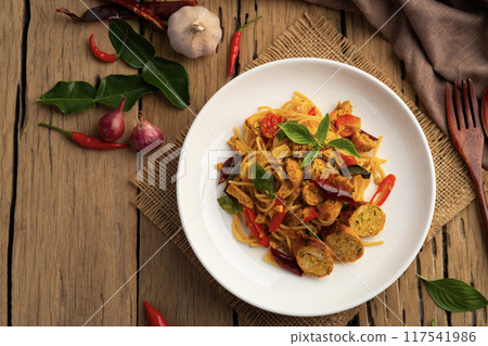 Stir fried Spaghetti with Northern Thai spicy sausage.pasta with chilli garlic and basil leaves in white plate.Thai fusion food.Top view. Stir fried Spaghetti with Northern Thai spicy sausage.pasta with chilli garlic and basil leaves in white plate.Thai fusion food.Top view. 117541986