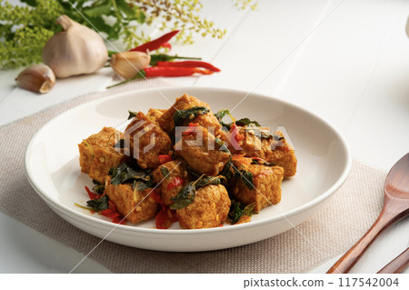 Stir fried basil with tofu.stir fry deep fried hard tofu soy bean curd with basil leave in white plate.Vegetarian food. 117542004
