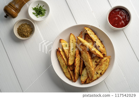 Air Fryer Roast Potatoes on white plate,potato wedges with tomatoes sauce.Top view. Air Fryer Roast Potatoes on white plate,potato wedges with tomatoes sauce.Top view. 117542029