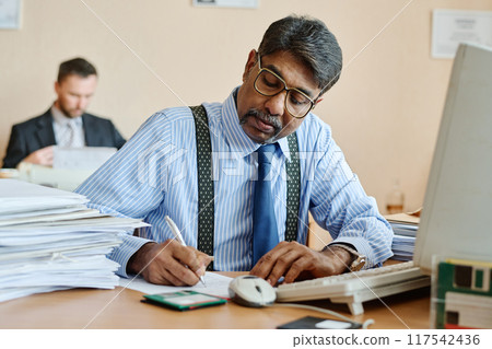 Manager Reviewing Documents at Office Desk 117542436