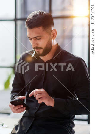 Young casual Businessman holding and using smartphone for sms messages Young casual Businessman holding and using smartphone for sms messages 117542741