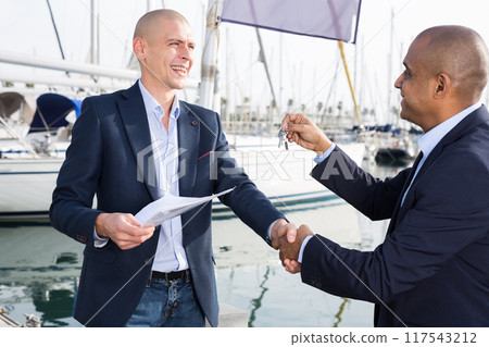 Two men in suits buy and sell a yacht in the seaport 117543212