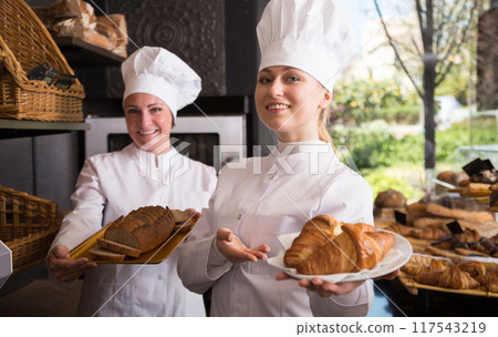 Women workers in a bakery posing with pastries Women workers in a bakery posing with pastries 117543219