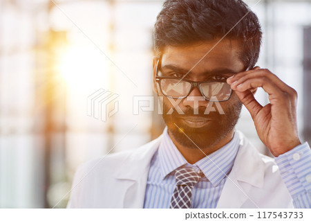 Portrait of a smiling male doctor standing in a hospital corridor Portrait of a smiling male doctor standing in a hospital corridor 117543733