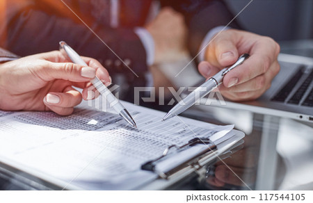 Close-up. Businessman looking at financial report and making notes with a pen in it 117544105