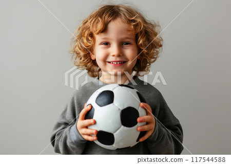 Radiant Youth with Sparkling Smile, Posing with Soccer Ball on Colored Surface 117544588