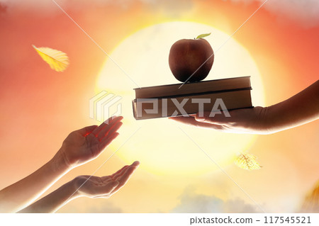Hand of adult giving a book to a child Hand of adult giving a book to a child 117545521