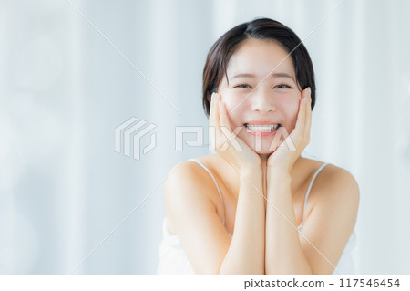 A young woman feels her skin become more moisturized A young woman feels her skin become more moisturized 117546454