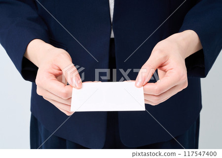 The hand of a woman in a suit handing over a business card 117547400