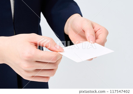 The hand of a woman in a suit handing over a business card 117547402