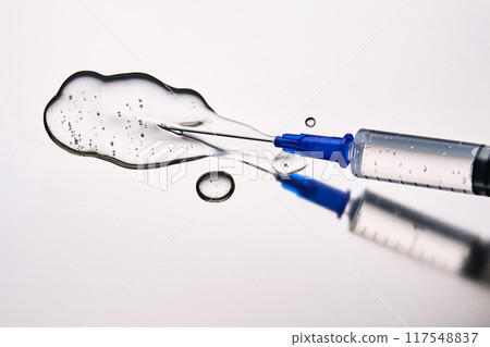 A drop of medicine flowing from a syringe with a needle. 117548837