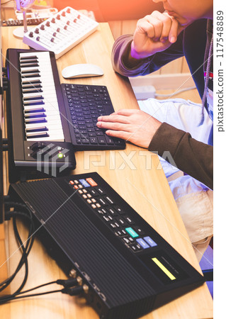 male music producer, arranger, composer listening music in home studio, showing professional recording equipment and musical instrument for music production 117548889