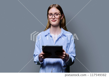 Teenage female student using digital tablet on gray studio background Teenage female student using digital tablet on gray studio background 117549382