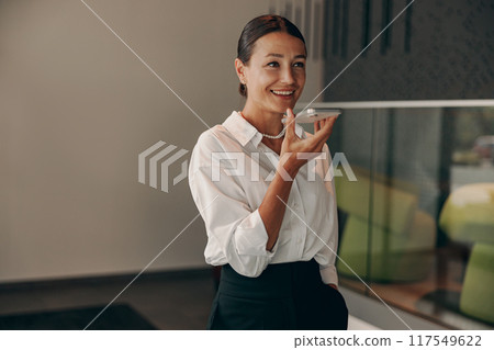 A confident woman engages in a conversation in a modern office, showcasing professionalism 117549622