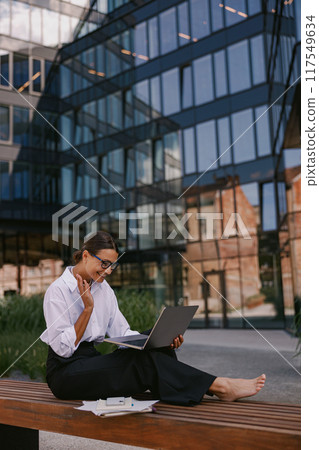A Young Professional Engaged in Productive Work Outdoors within a Modern Office Environment A Young Professional Engaged in Productive Work Outdoors within a Modern Office Environment 117549634