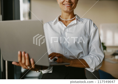 A Professional Woman Engaged in Working on a Laptop Within a Modern Office Environment 117549647