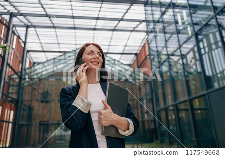 A professional businesswoman is having a phone conversation in a modern office setting A professional businesswoman is having a phone conversation in a modern office setting 117549668