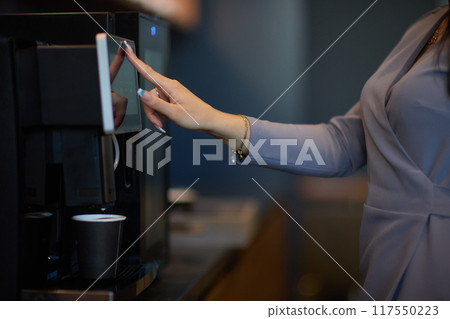 Professional using a touchscreen coffee machine for a convenient coffee break at work Professional using a touchscreen coffee machine for a convenient coffee break at work 117550223