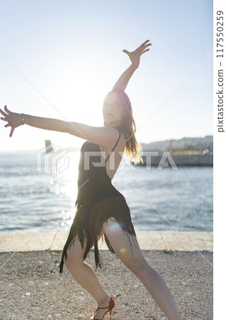 Young woman dancing latin dance by the sea at sunset 117550259