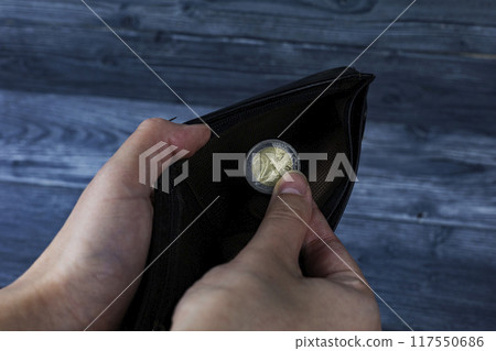 A person is firmly holding a shiny coin in their hand with care A person is firmly holding a shiny coin in their hand with care 117550686