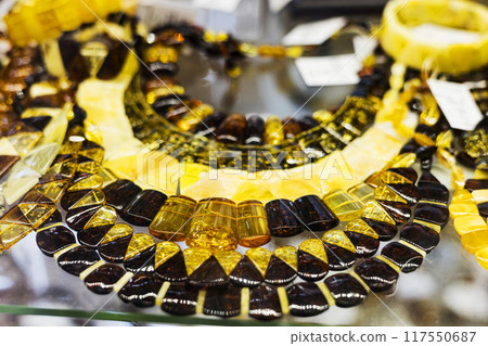 Necklaces amber of different colors and sizes on Jomas street in Majori, Jurmala. Souvenir or gift of stones of amber for tourists. Sun stone. Necklaces amber of different colors and sizes on Jomas street in Majori, Jurmala. Souvenir or gift of stones of amber for tourists. Sun stone. 117550687