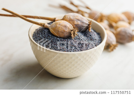 Dry poppy head and poppy seed in bowl on kitchen table. Dry poppy head and poppy seed in bowl on kitchen table. 117550751