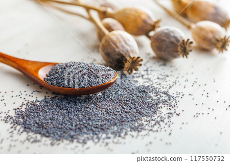 Dry poppy head and poppy seed in spoon on kitchen table. Dry poppy head and poppy seed in spoon on kitchen table. 117550752