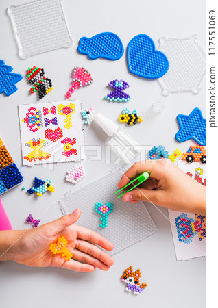 Girl making a key from aqua beads at her workplace top and vertical view Girl making a key from aqua beads at her workplace top and vertical view 117551069