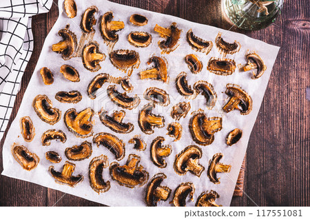 Baked spicy mushroom chips on paper on a wooden board top view Baked spicy mushroom chips on paper on a wooden board top view 117551081