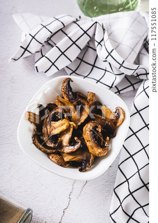 Crispy baked shiitake chips with spices in a bowl on the table vertical view Crispy baked shiitake chips with spices in a bowl on the table vertical view 117551085