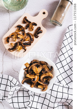 Crispy baked shiitake chips with spices in a bowl on the table top and vertical view Crispy baked shiitake chips with spices in a bowl on the table top and vertical view 117551088