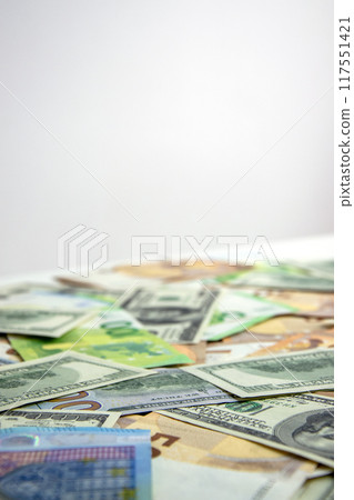 A close-up shot of a pile of US dollar and euro banknotes scattered on a white surface A close-up shot of a pile of US dollar and euro banknotes scattered on a white surface 117551421