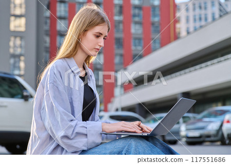Young female college student using laptop computer outdoor Young female college student using laptop computer outdoor 117551686